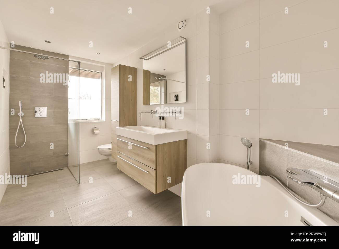 Interior of contemporary bathroom with glass shower cabin and stylish bathtub placed near sinks under mirror at home Stock Photo