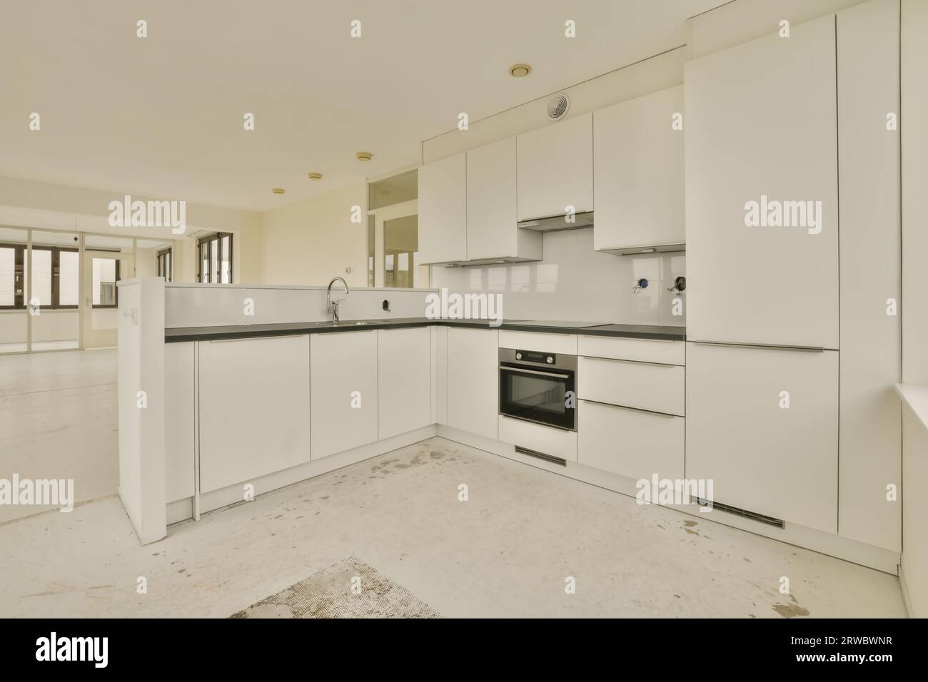 Interior of open plan modern kitchen with white cabinets and black counter in new spacious light apartment Stock Photo