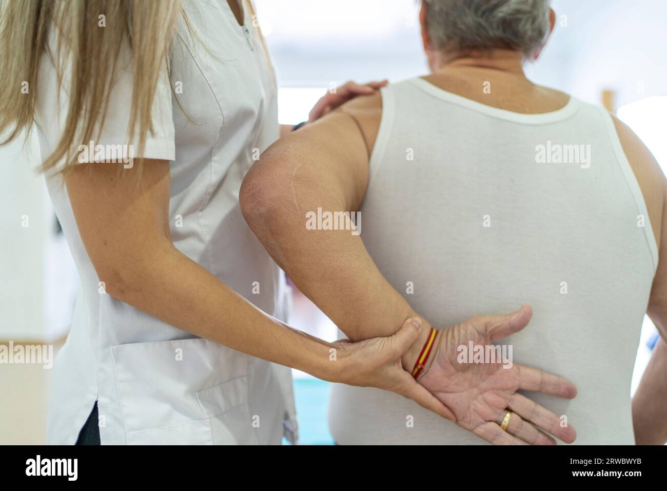 Unrecognizable female doctor in uniform treating elderly male patient during psychotherapy session in light modern hospital Stock Photo