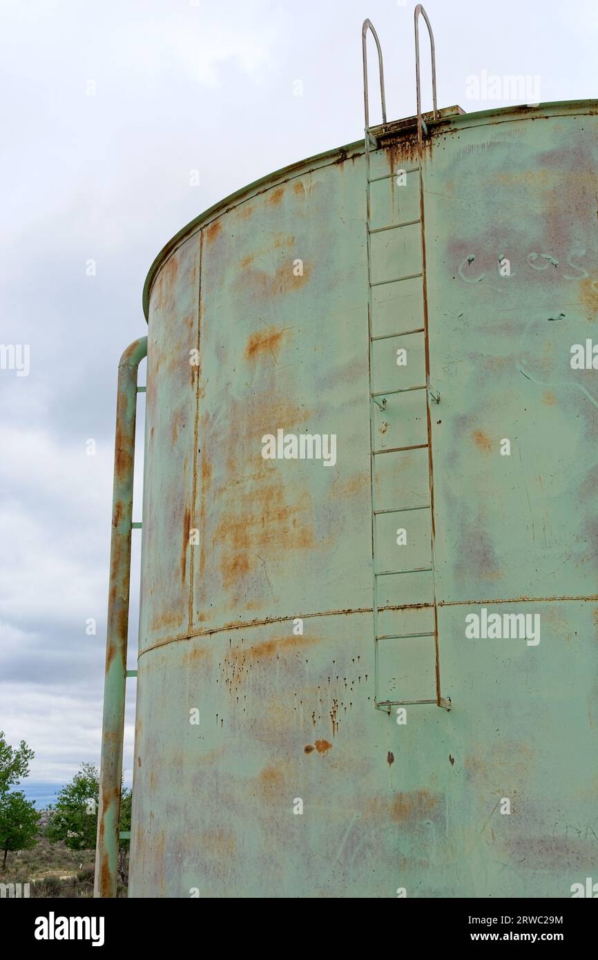 Weathered abandoned steel water tower tank with access ladder Stock