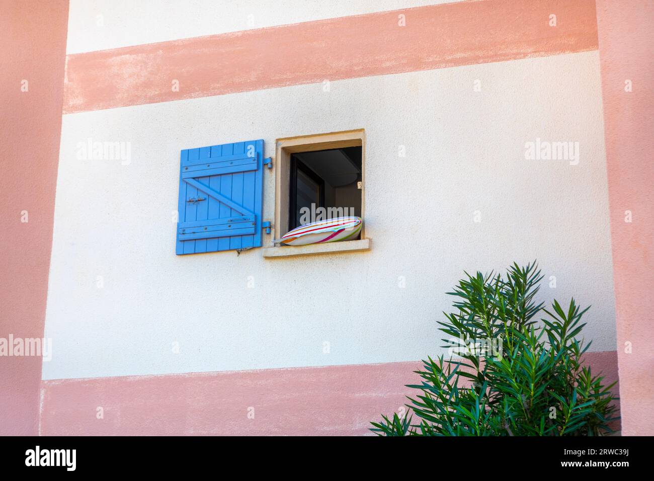 An open glassless window with a blue wooden shutter. Stock Photo