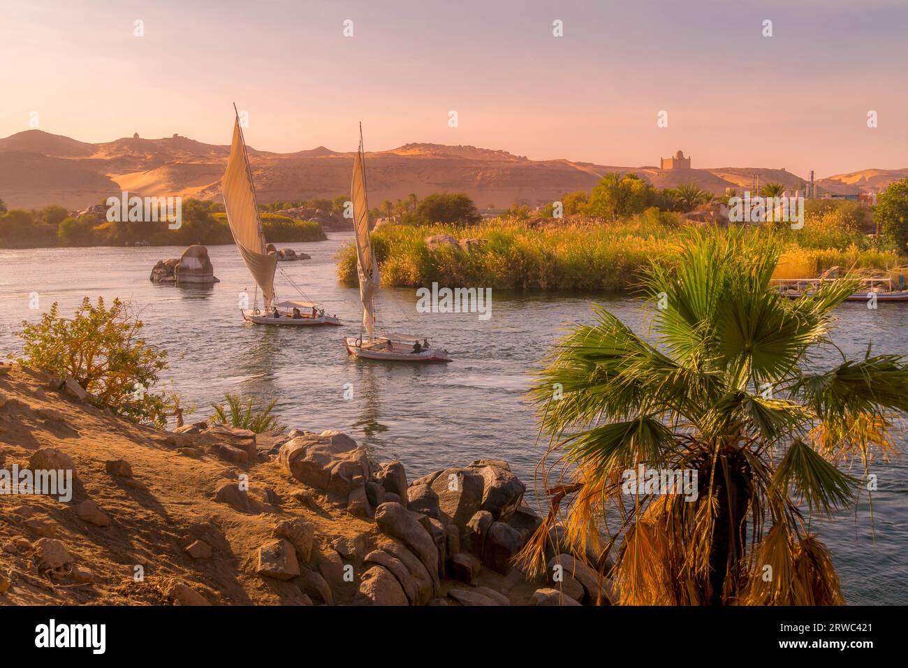 Boats sailing in Nile River during the sunset in Aswan, Egypt. Stock Photo