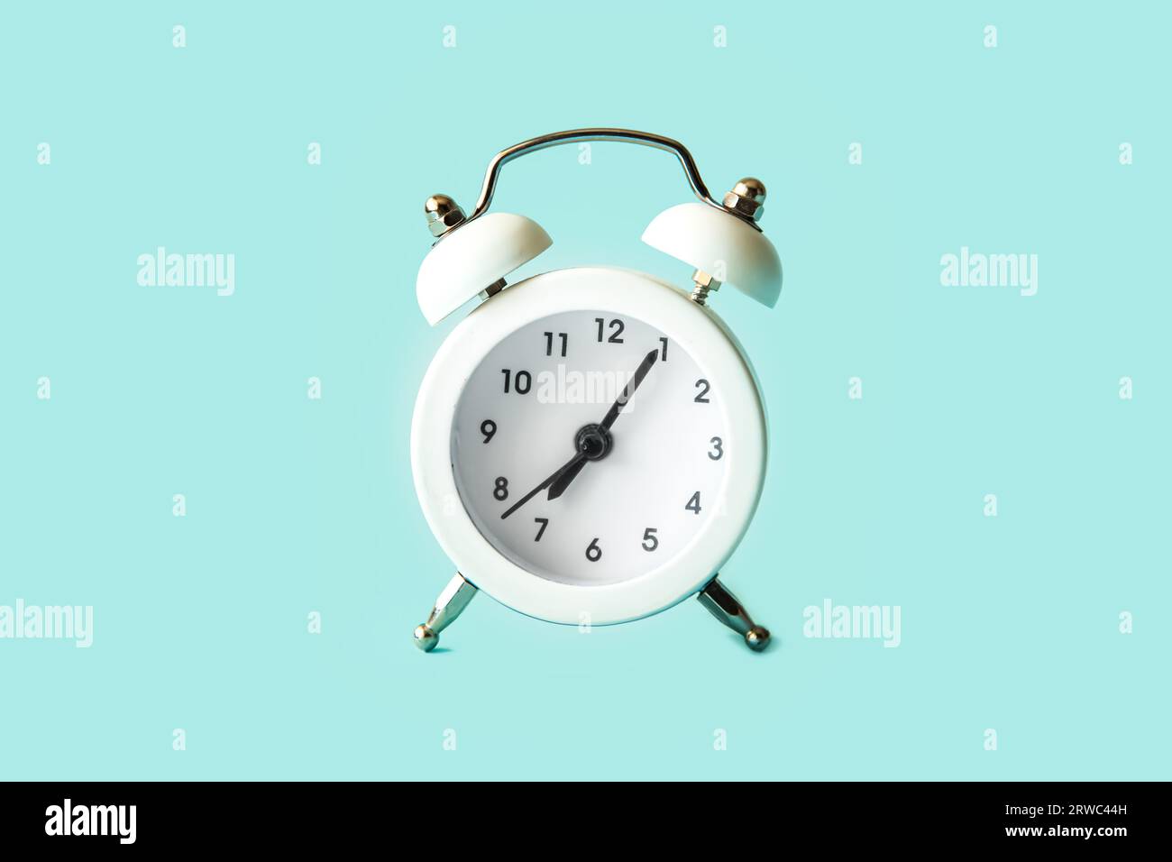 Vintage white alarm clock isolated on blue background. Stock Photo