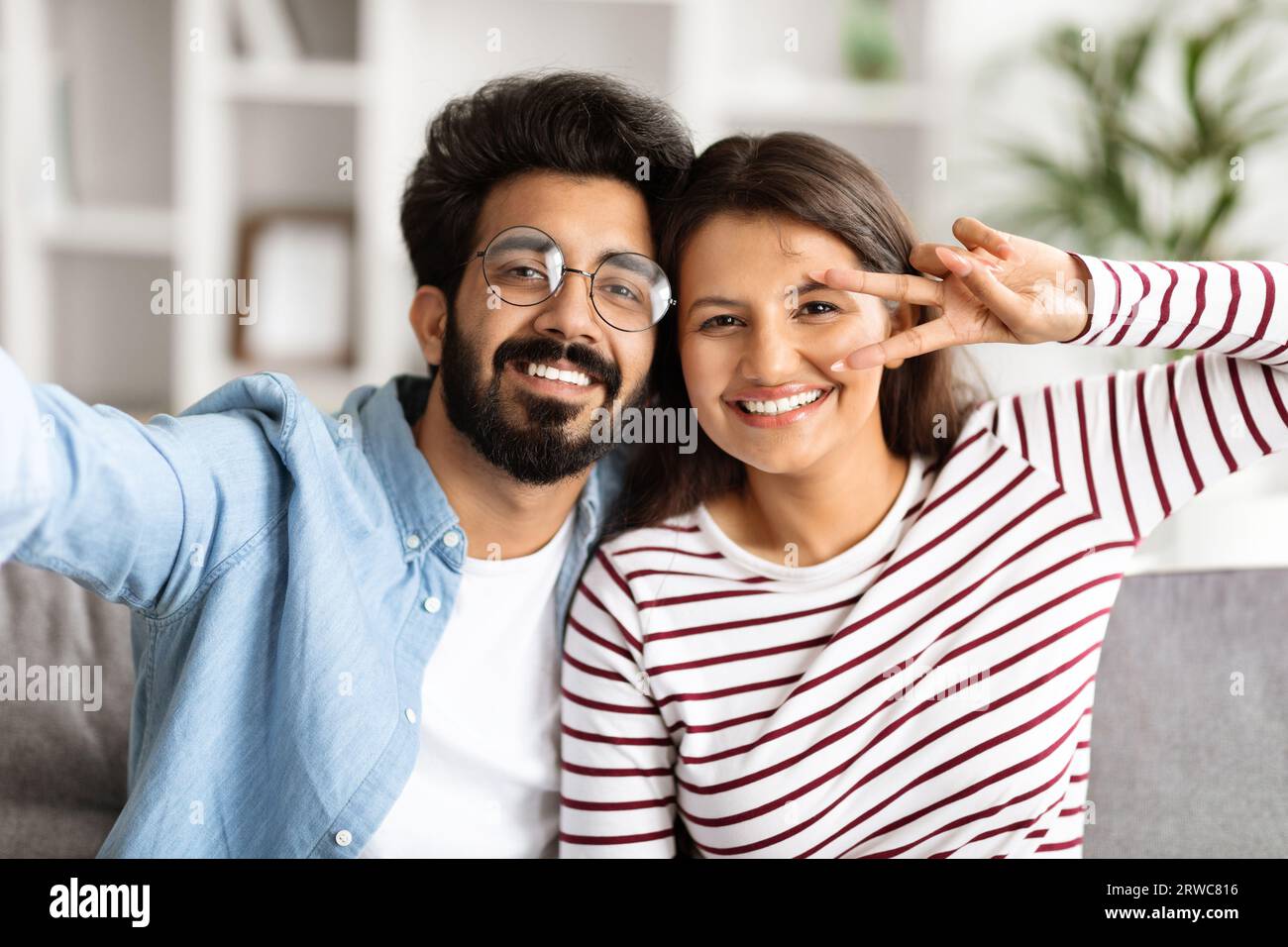 Happy millennial indian couple taking selfie at home Stock Photo