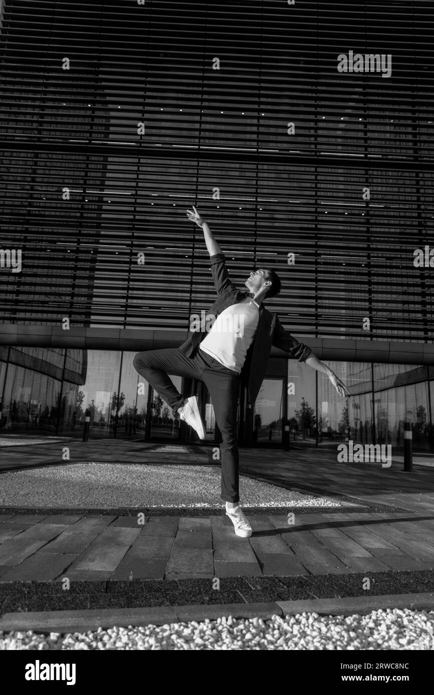 young attractive dancer in casual cloth doing ballet jump on the urban Stock Photo