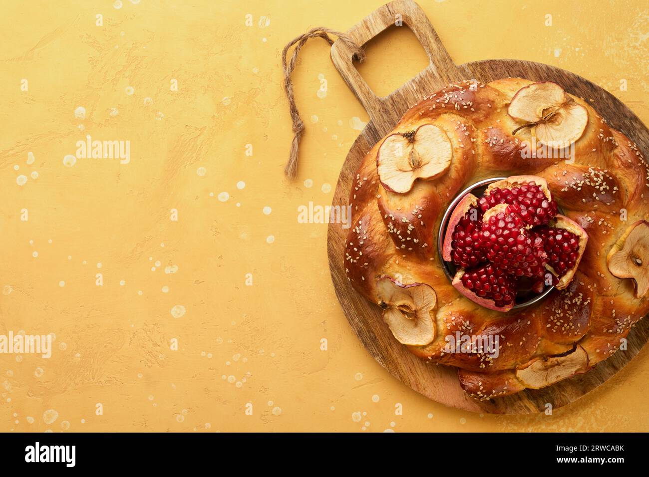 Jewish Holidays - Rosh Hashanah or Rosh Hashana. Pomegranate, apples, honey and round challah on rustic yellow table background. Jewish Autumn celebra Stock Photo