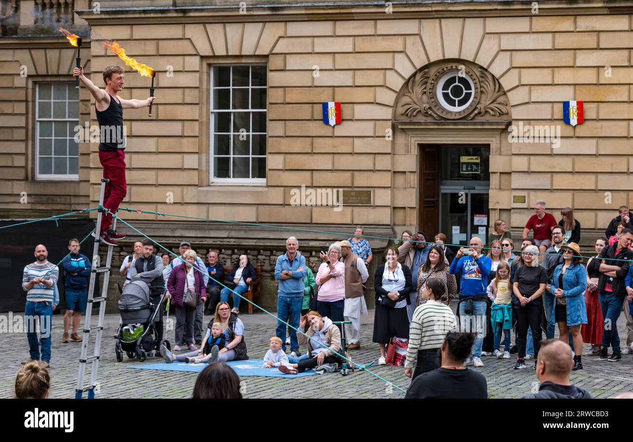 Street performer juggling fire torches while standing on a ladder, Edinburgh Festival Fringe, Parliament Square, Scotland, UK Stock Photo