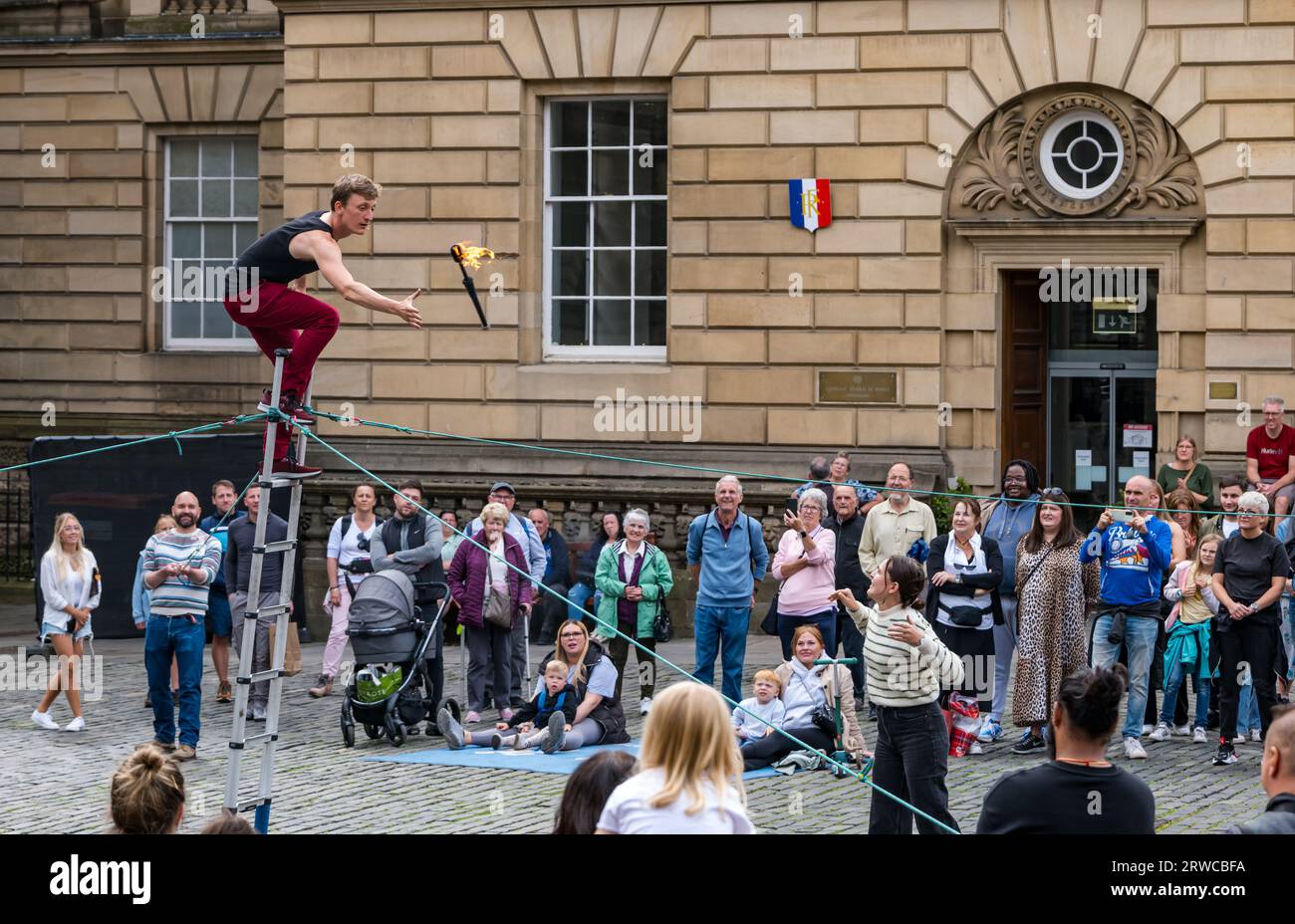 Street performer juggling fire torches while standing on a ladder, Edinburgh Festival Fringe, Parliament Square, Scotland, UK Stock Photo