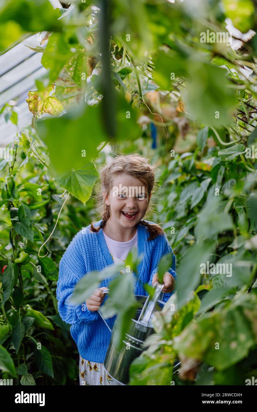 Portrait of a young girl standing in a greenhouse in the middle of ...
