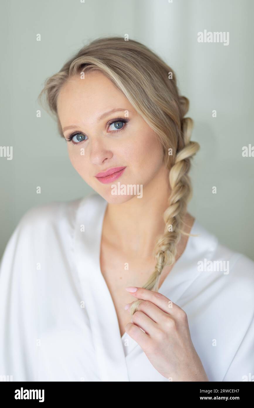 Beautiful blonde girl with braided hair in white dressing gown Stock Photo