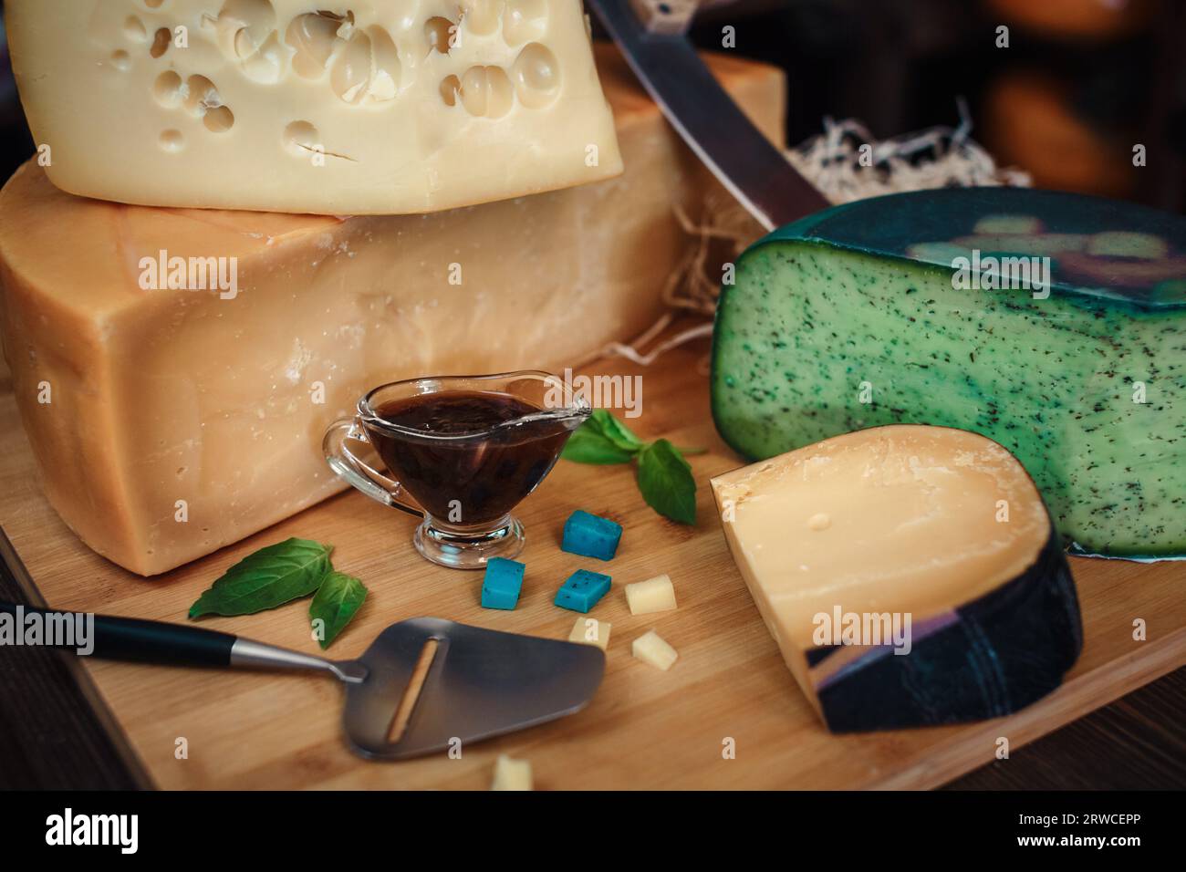 Cheese heads with slices and knives lie on a wooden board with an interior Stock Photo