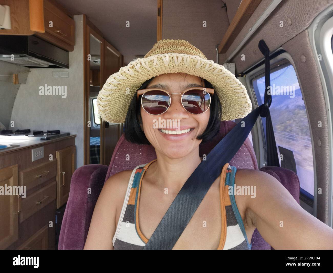 Young Asian woman taking selfie from passenger seat inside a camper van vehicle. Freedom travel on the road in British Columbia, Canada. Stock Photo