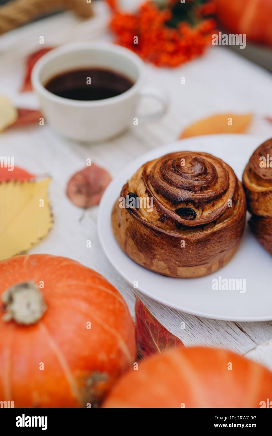 bun, pastry on tray with drink and autumn decoration: fallen yellow leaves and pumpkins. autumn mood Stock Photo