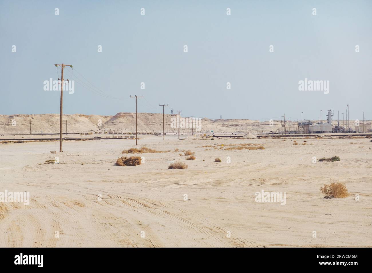 power lines head across the desert to a natural gas facility in the Middle Eastern state of Bahrain Stock Photo