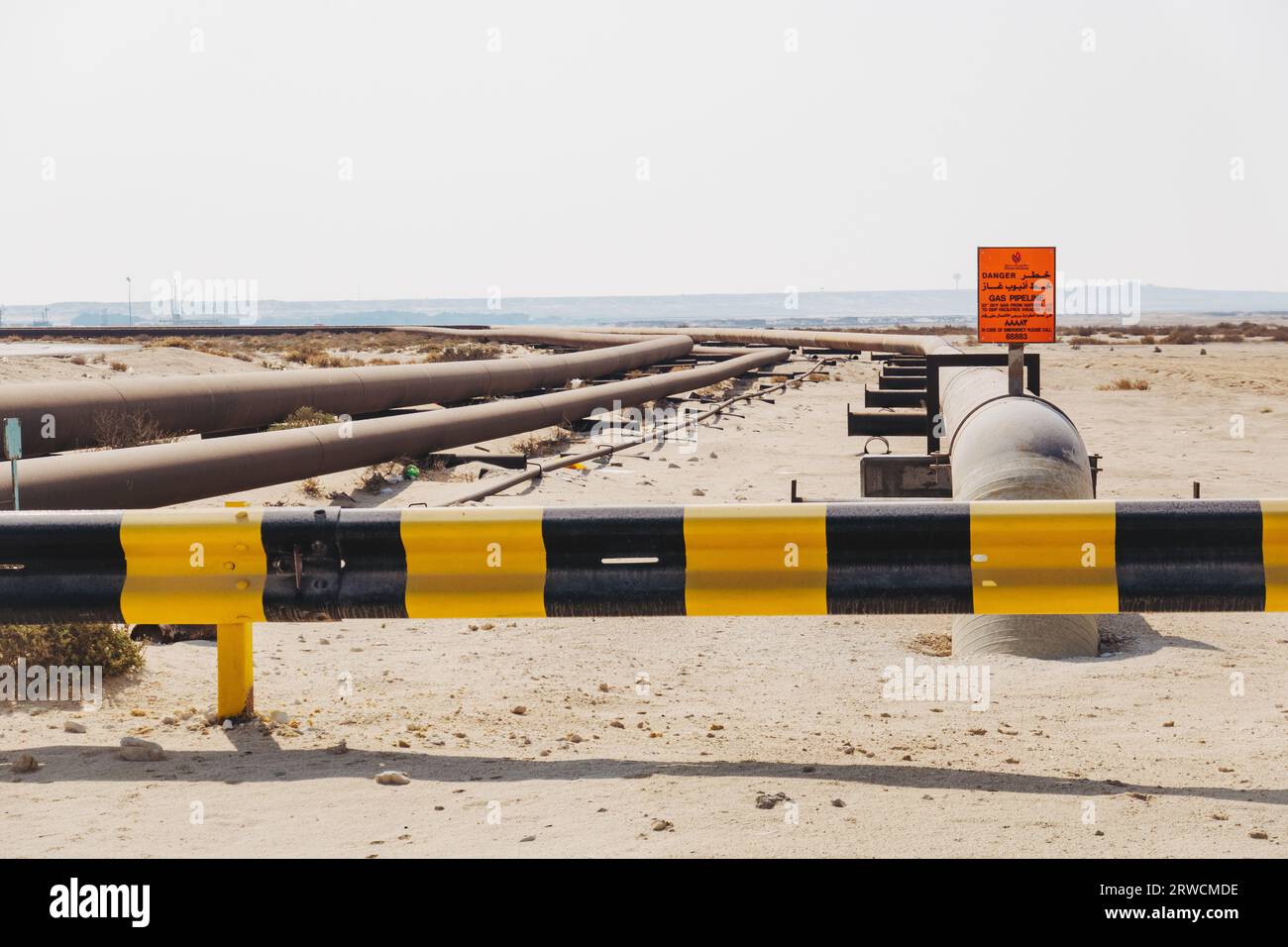 a natural gas pipeline with a warning sign in the Bahraini desert Stock Photo