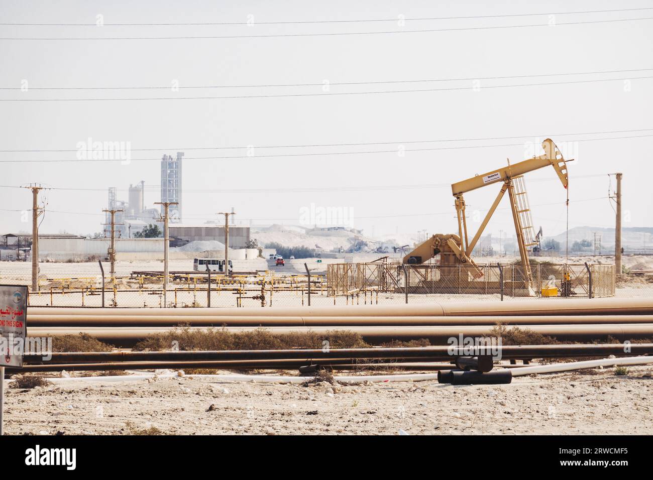 a natural gas extraction well and pipelines in the desert in Bahrain Stock Photo
