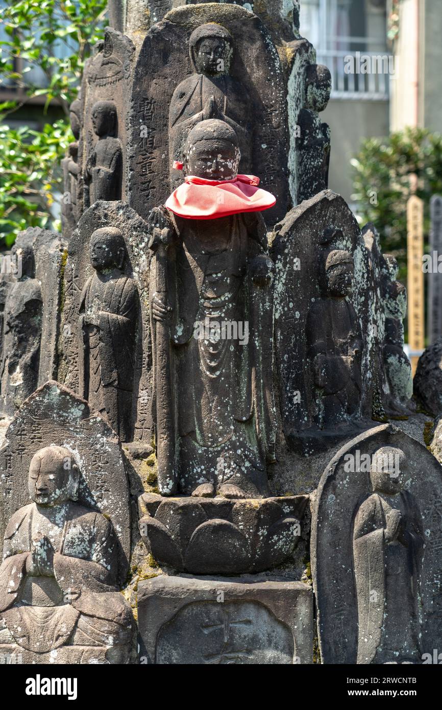 Traditional Buddhist style tomb markers with a Jizo Bosatsuat statue and red bib at small