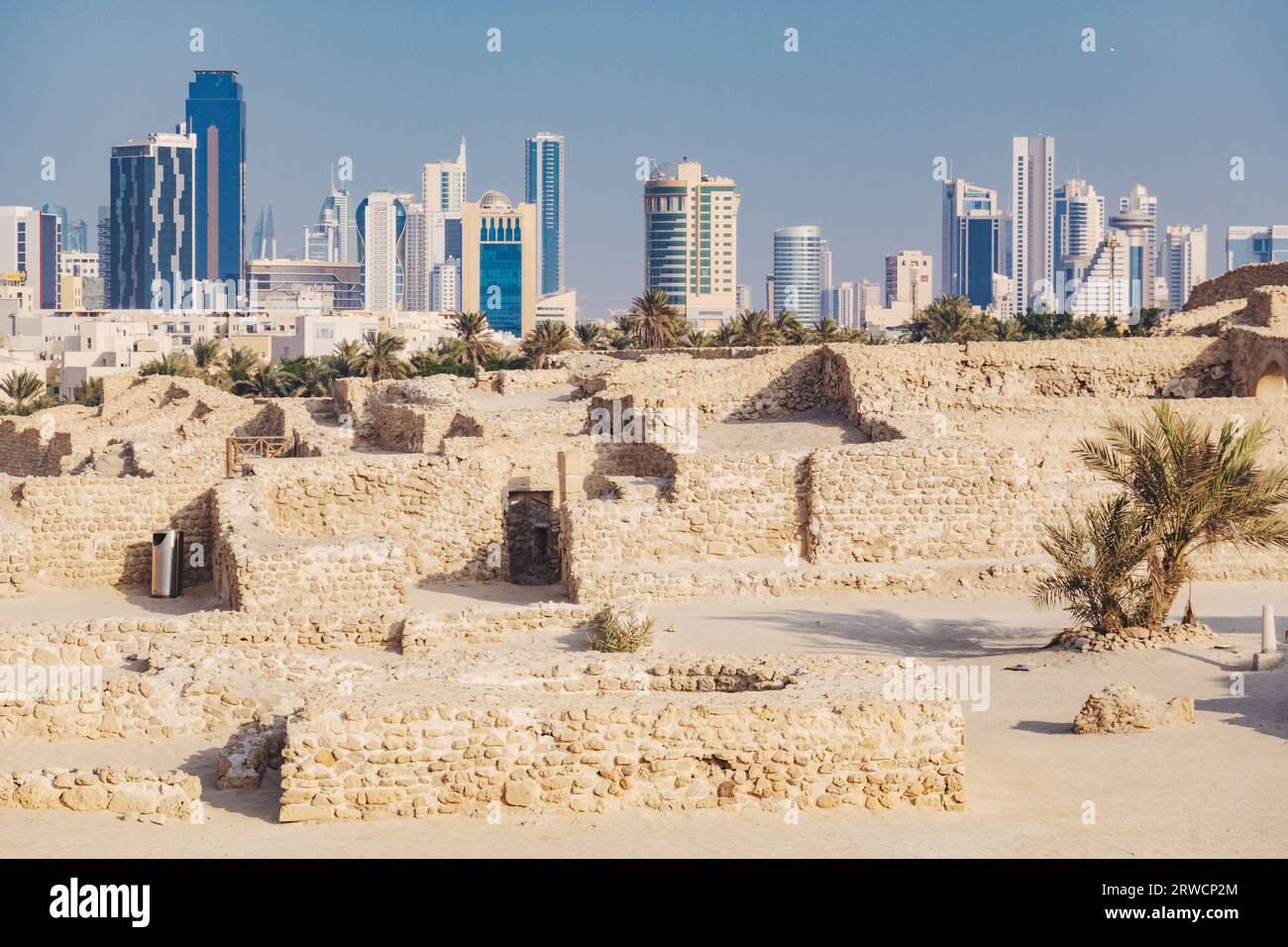Old and new: the stone wall ruins of Bahrain Fort, dating back to 2300 BCE, against the skyline of downtown Manama city Stock Photo