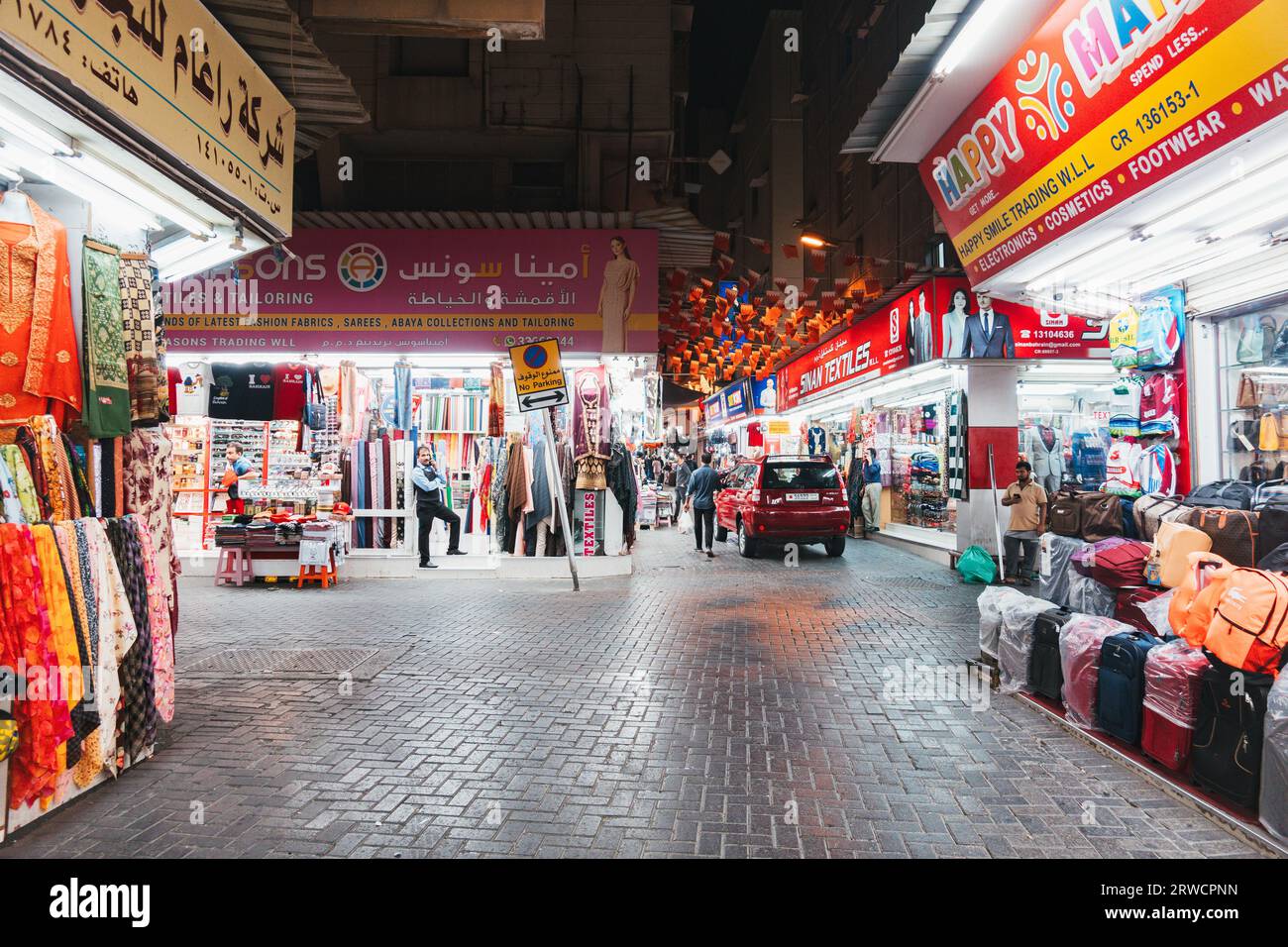 a street full of shops selling clothing, toys and other household items in the Manama Souq, Bahrain, at night Stock Photo