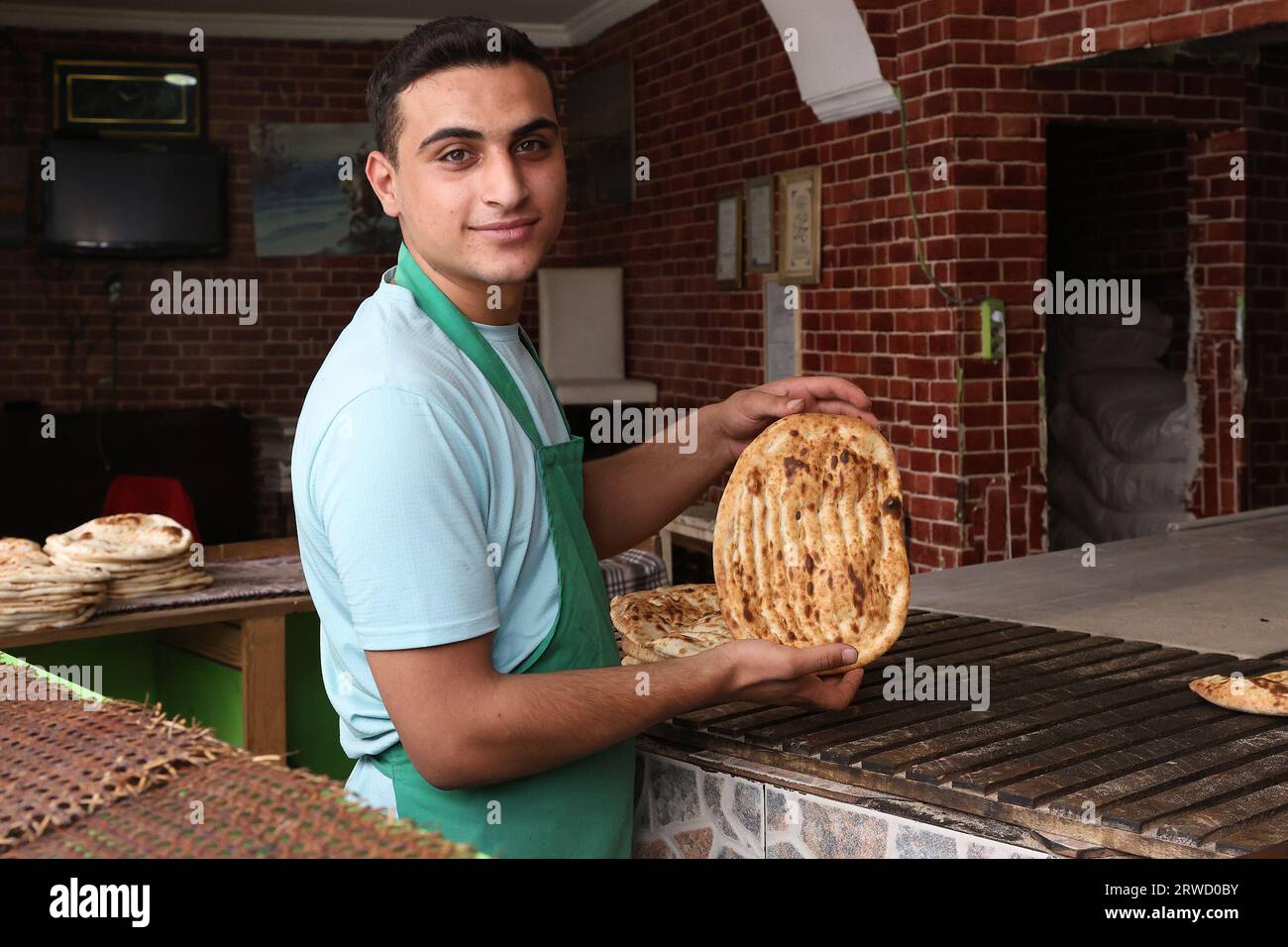 Portrait of a baker holding a piece of freshly-made flatbread at a bakery in the Fatih district of Istanbul, Turkey Stock Photo