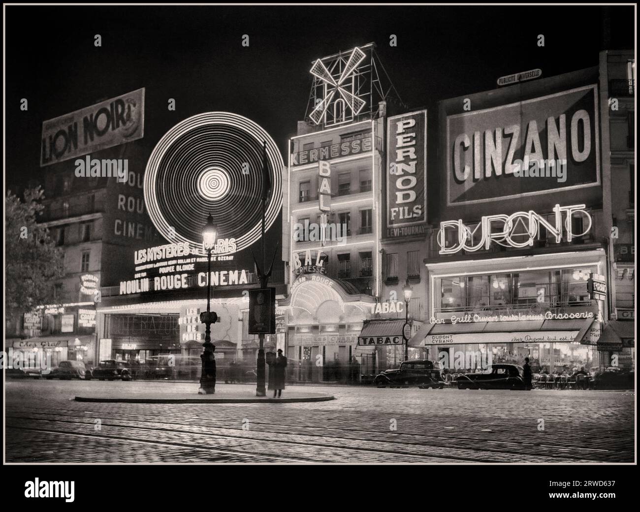 Retro Vintage Paris B&W 1930’s The Moulin Rouge Historic Montmartre Paris France at night  Alcohol Drinks Advertising Hoardings, Cinzano, Pernod, DuPont. Lion Noir. 1936: France, Paris Moulin Rouge Photographer :  Willem van de Poll Stock Photo