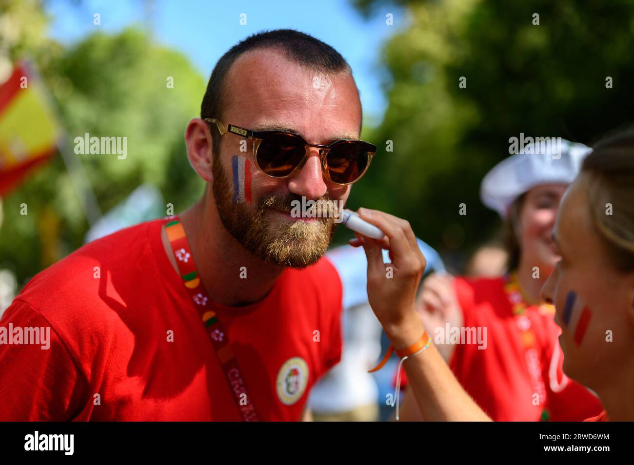 A French pilgrim – a young man – having his cheeks painted with French national colours during World Youth Days in Lisbon, Portugal. Stock Photo