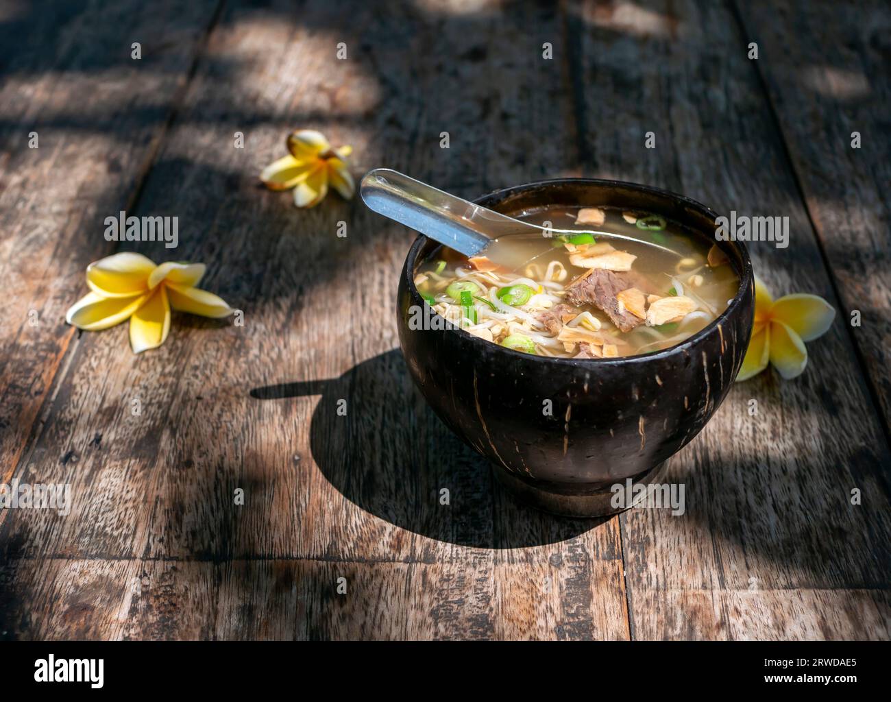 Soto Batok, a traditional Javanese beef soup with vegetables and rice, served in a traditional bowl made of coconut shell. Stock Photo