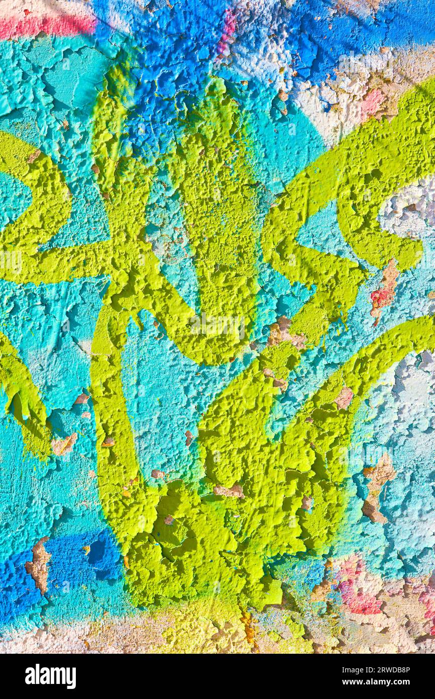 Paint peeling from a concrete wall where graffiti has been spraypainted. Stock Photo
