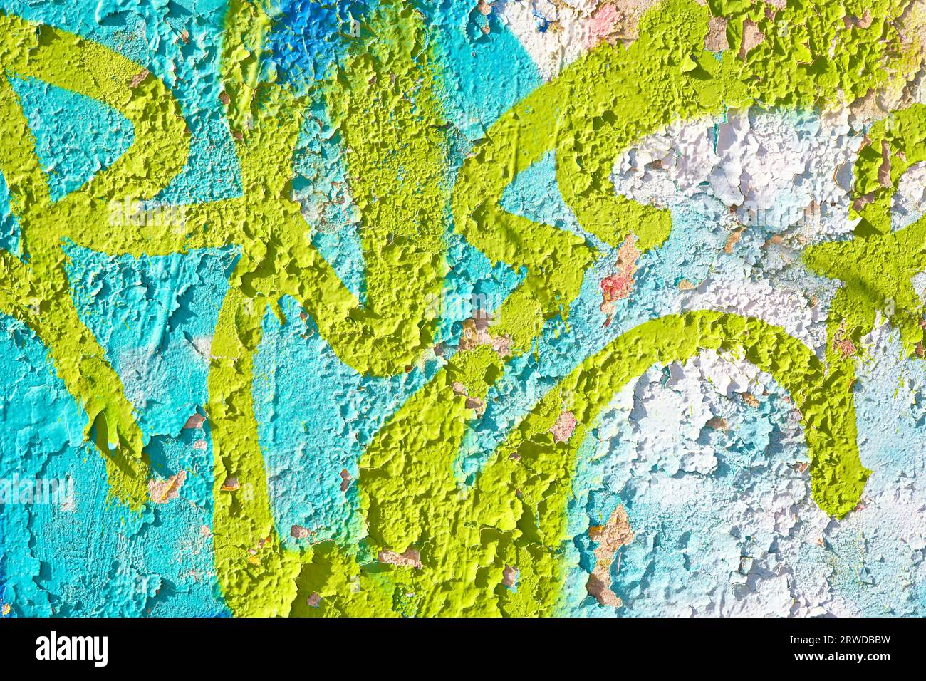 Paint peeling from a concrete wall where graffiti has been spraypainted. Stock Photo