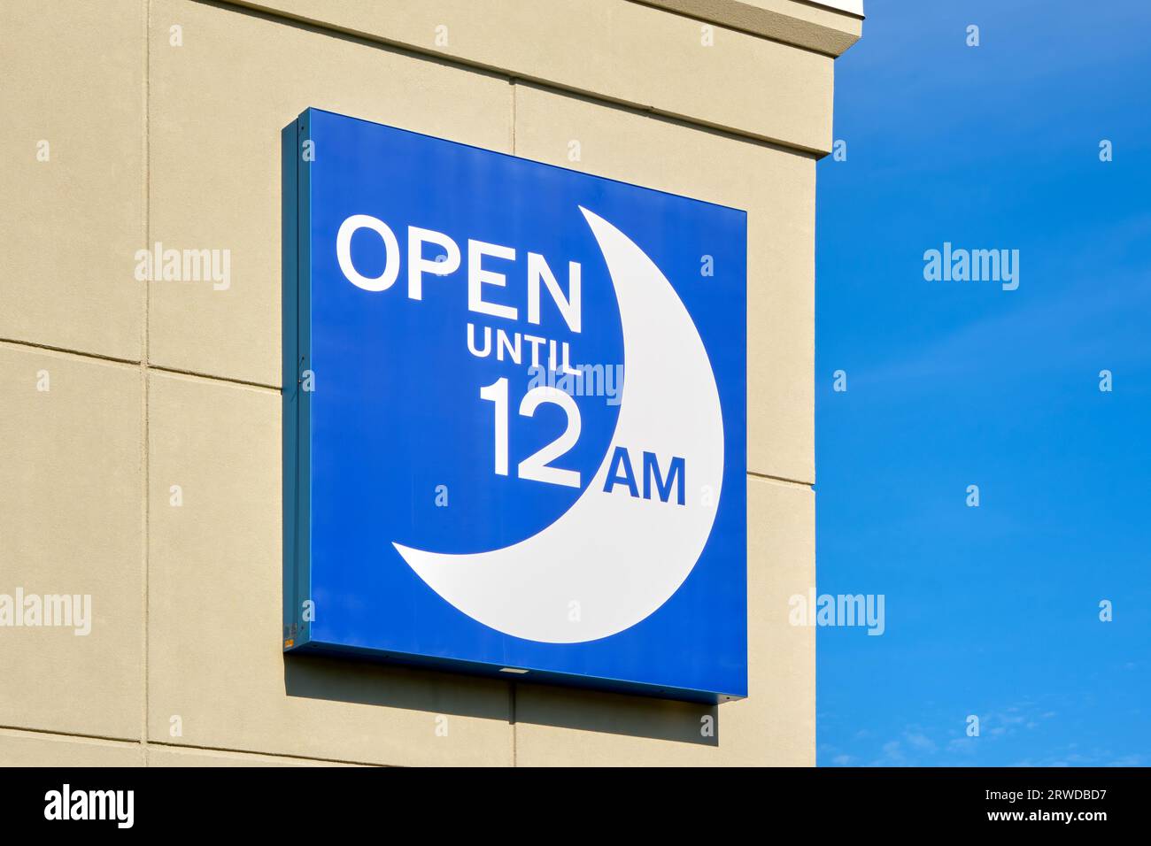Sign affixed to a Shoppers Drug Mart store informing customers that the location is open late night. Stock Photo