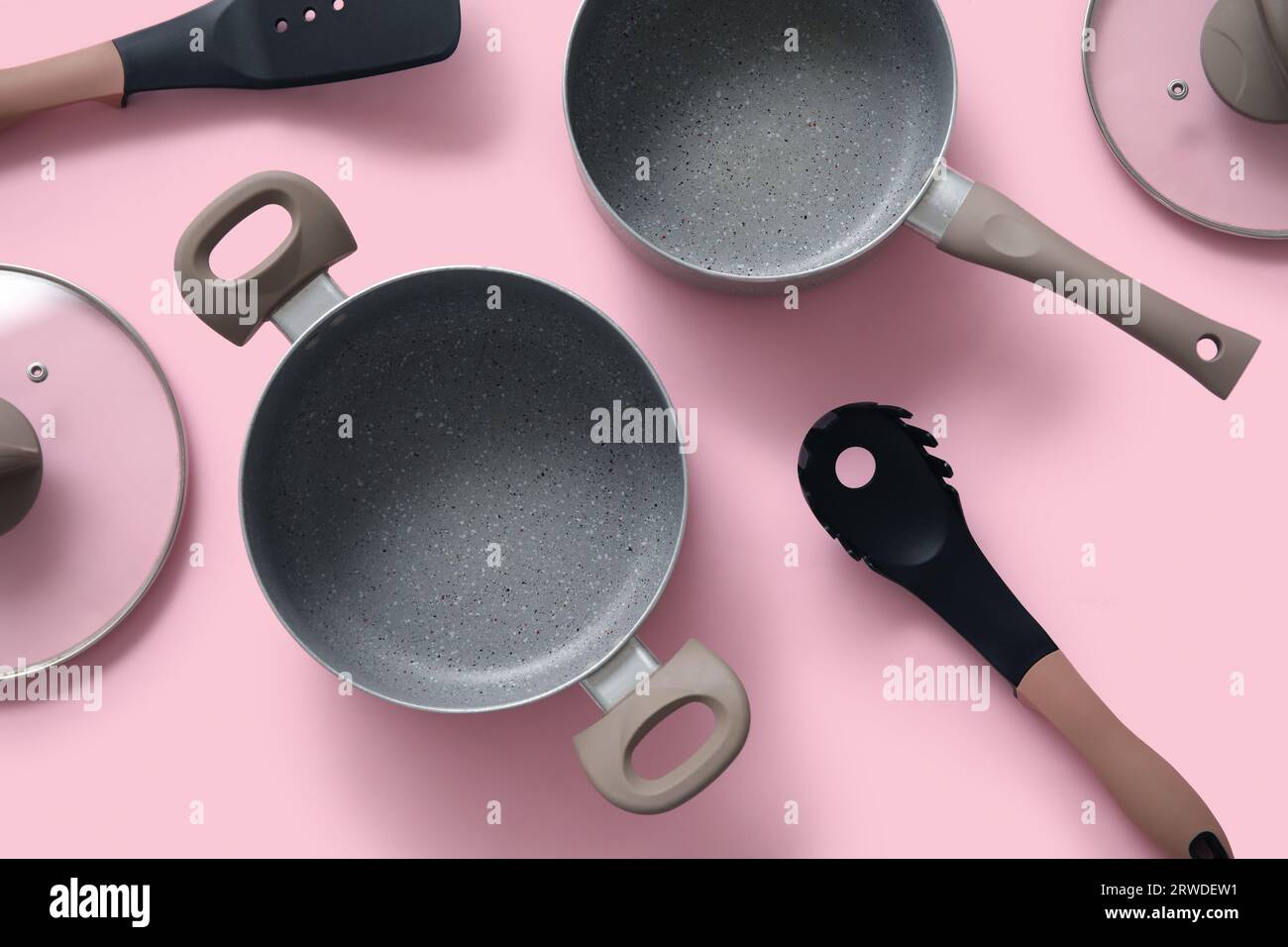 Cooking pots and kitchen utensils on pink background Stock Photo