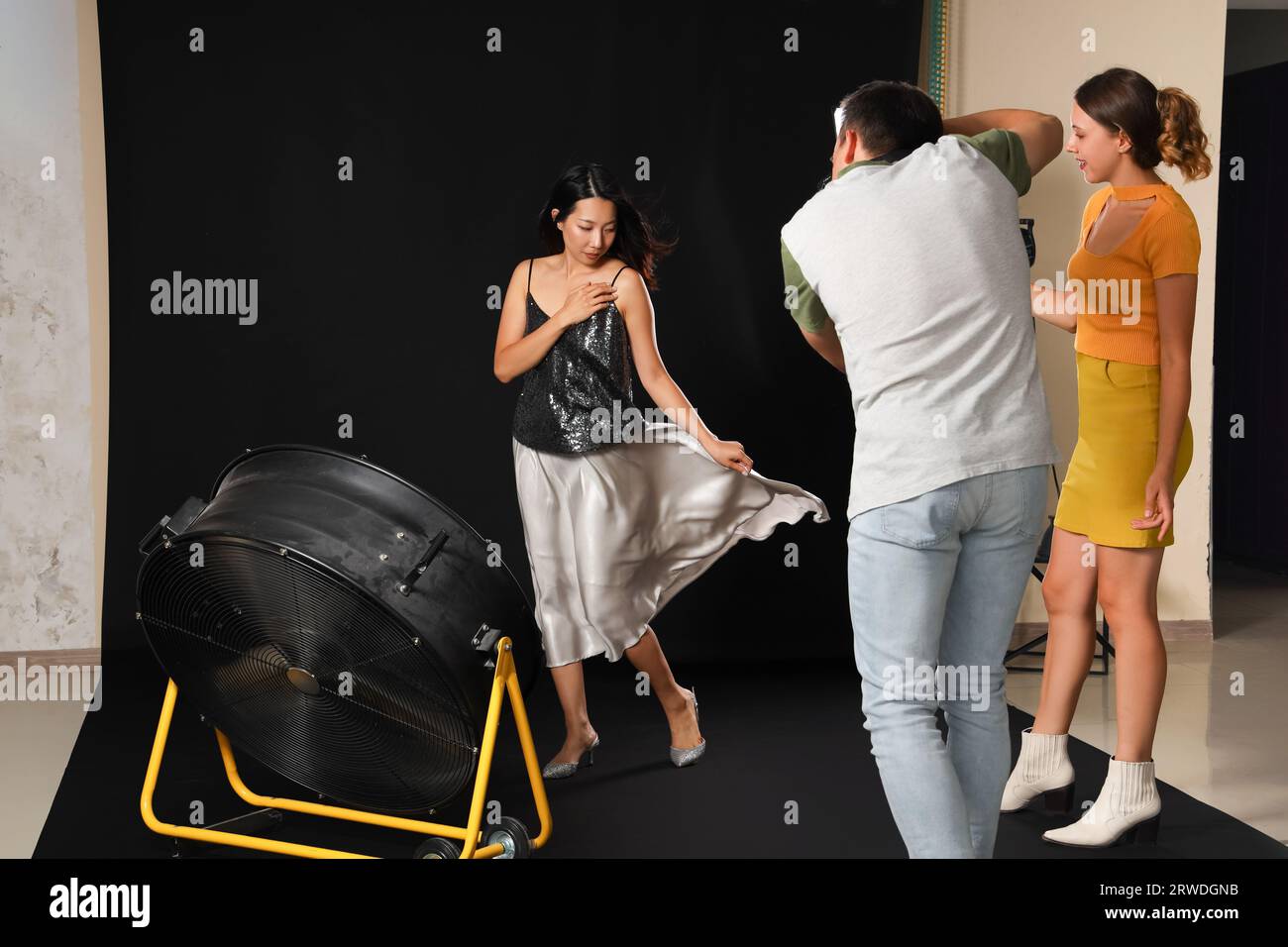 Male photographer and his assistant working with Asian model in studio ...