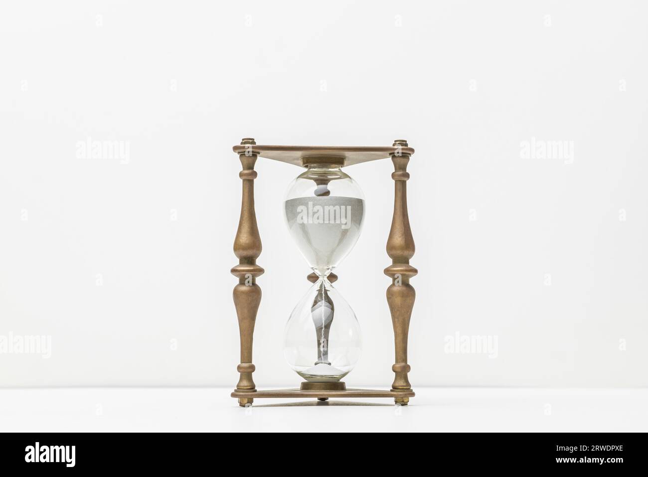 Hourglass sand glass timer time clock device historical old white backdrop clean empty space Stock Photo