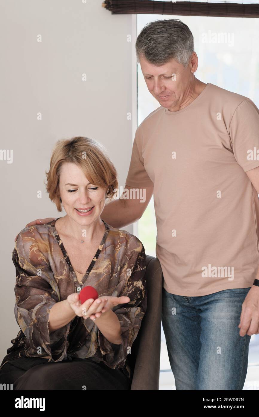 happy couple in their 50's looking at red velvet gift box with jewellery item. anniversary celebration. middle age couple family Stock Photo