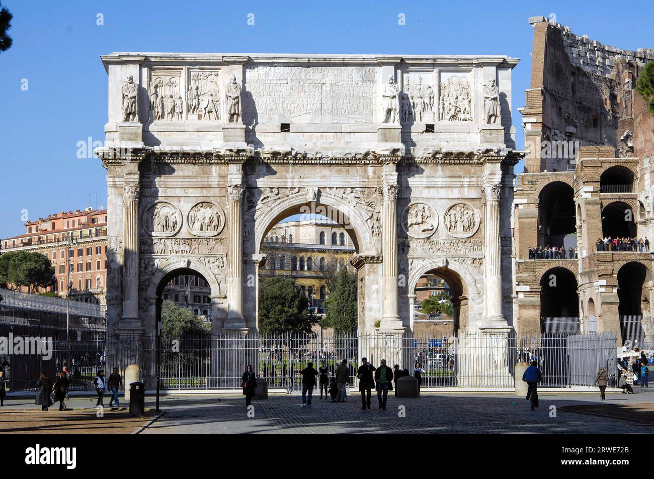 Frontal view of Arch of Constantine Triumphal Arch of Emperor Constantine with few people tourists, at the right edge of the picture Colosseum, Rome Stock Photo