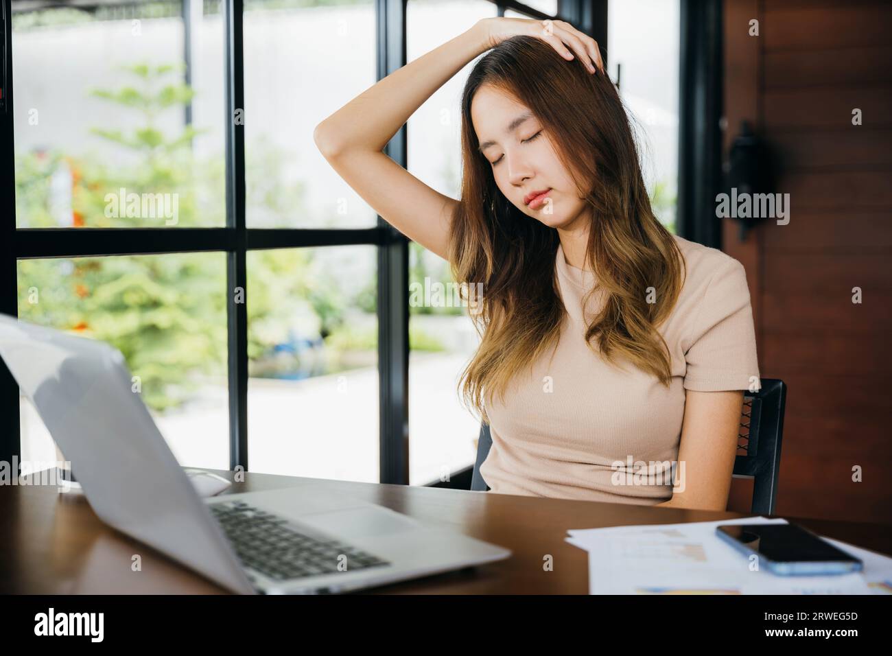 Tired office woman sitting at desk touching massaging stiff neck while ...