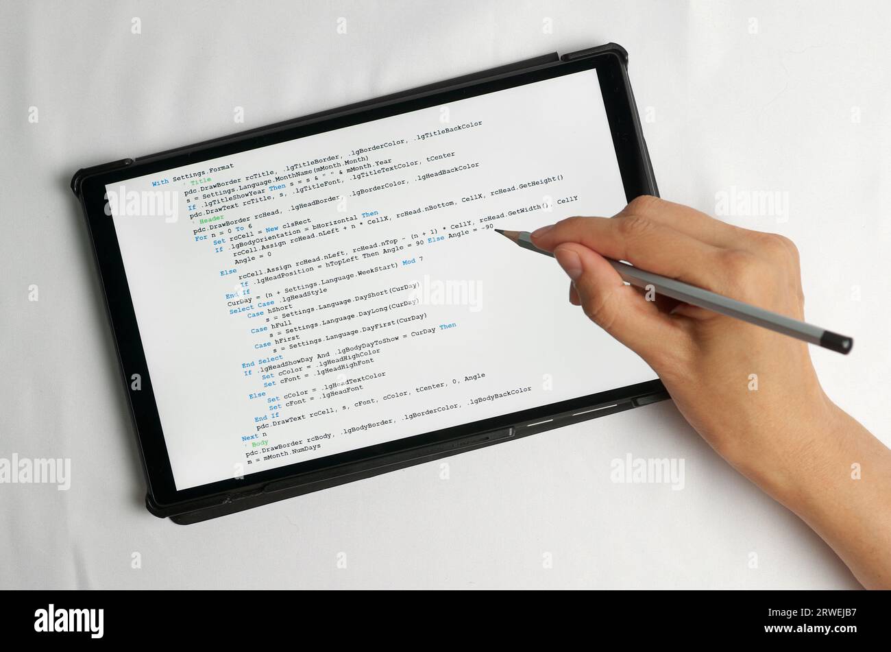 Programming and coding concept. A hand with a pencil writes a program listing on the screen Stock Photo