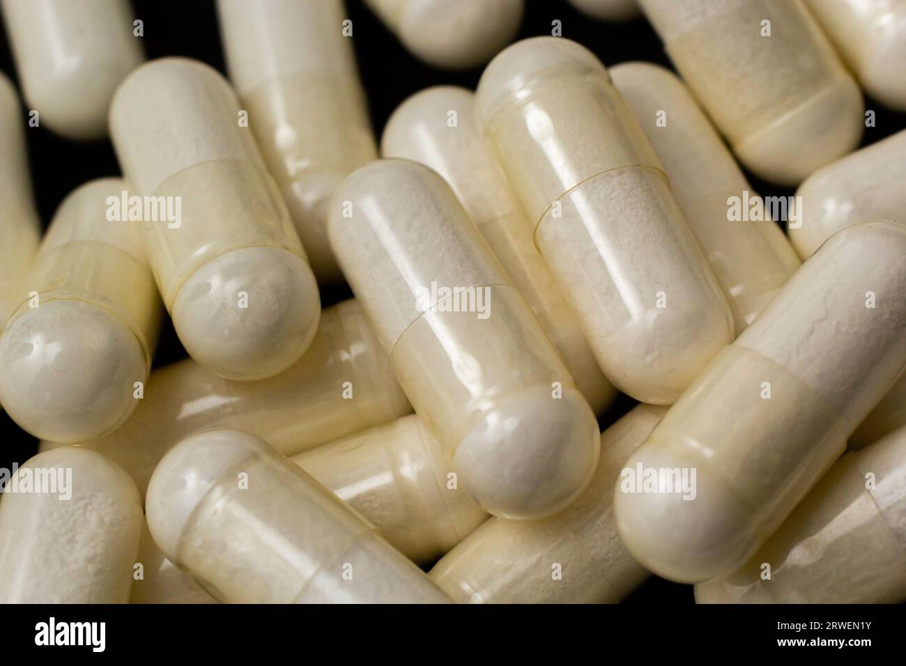 Macro Close up of white painkiller tablet on a reflective black background. Stock Photo