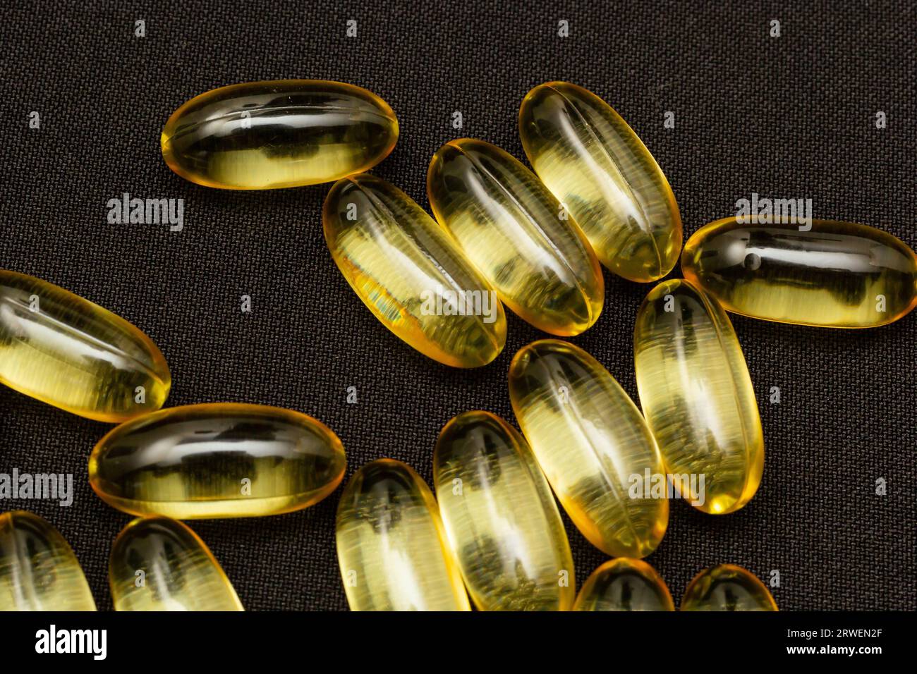 Macro Close up of Omega 3 gel capsule on a reflective black background. Stock Photo