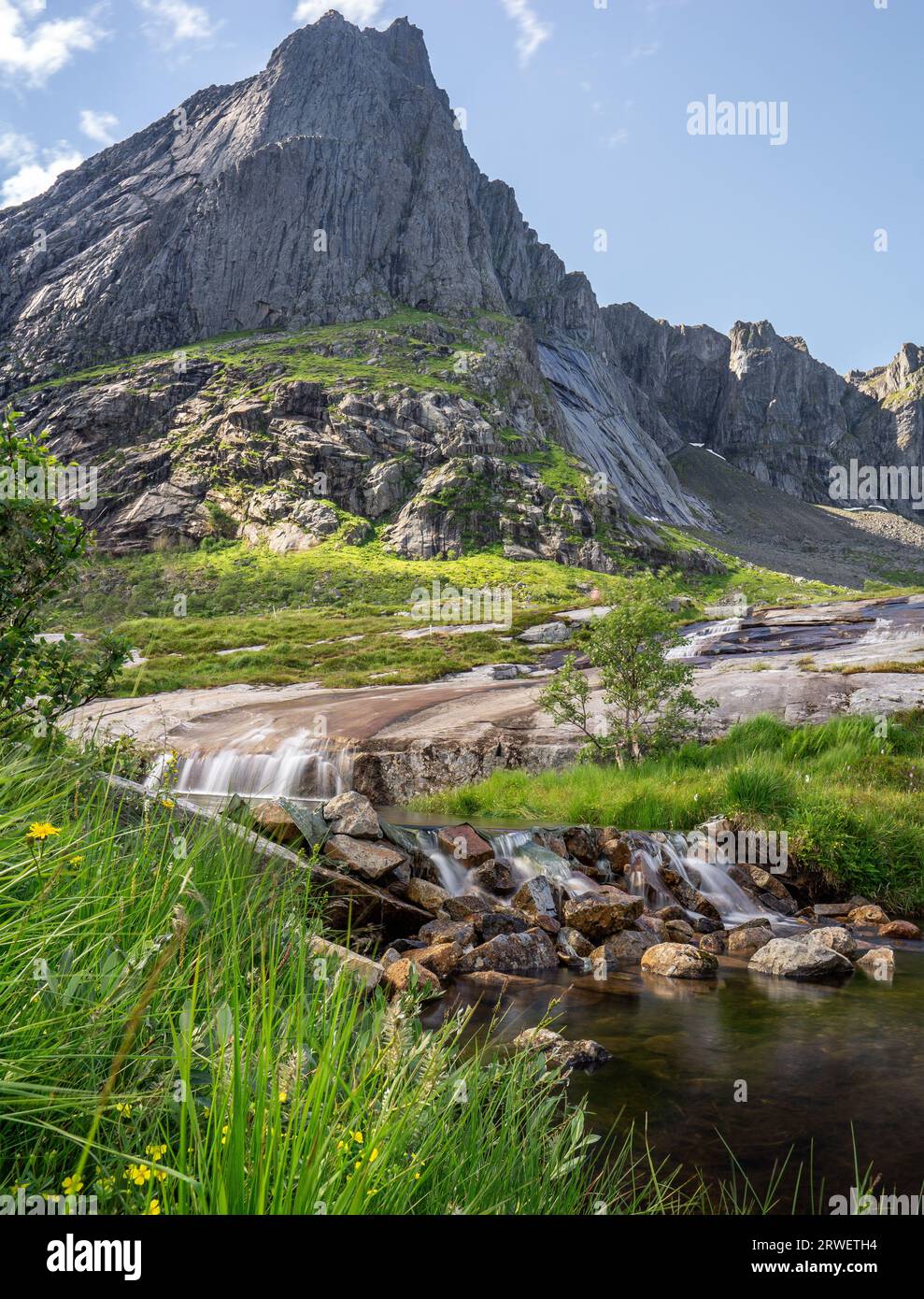 Summer's Serenade: Molneva Waterfall Cascading Against a Mountainous Tapestry Stock Photo