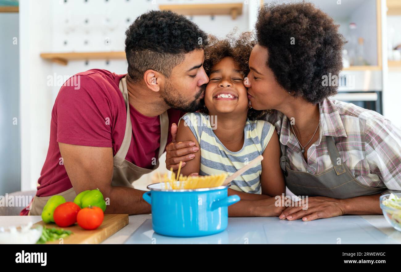 Overjoyed young african american family with kid have fun cooking at home together, Stock Photo