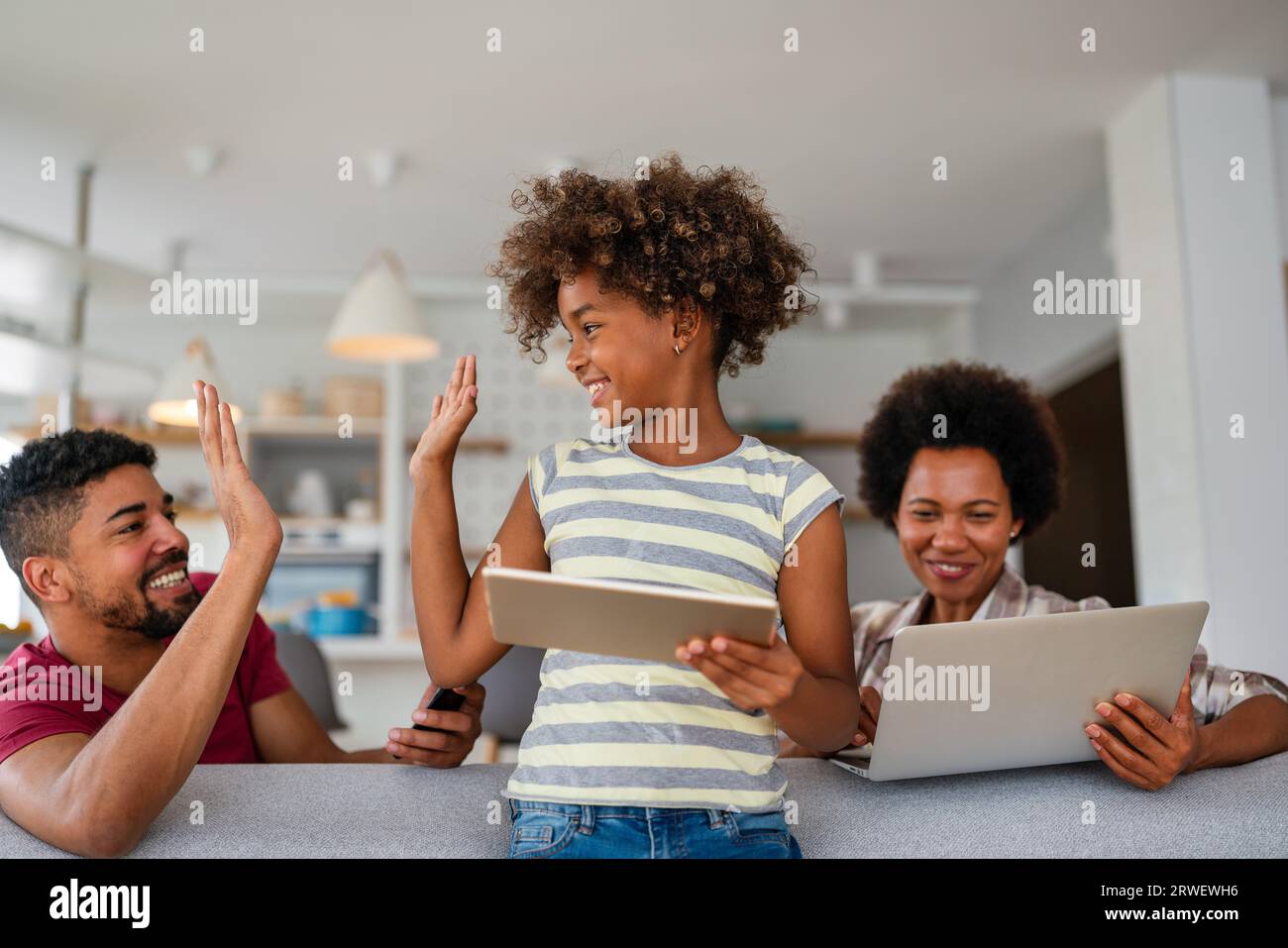 Planning vacation together. African american father, mother and daughter using computer at home, Stock Photo