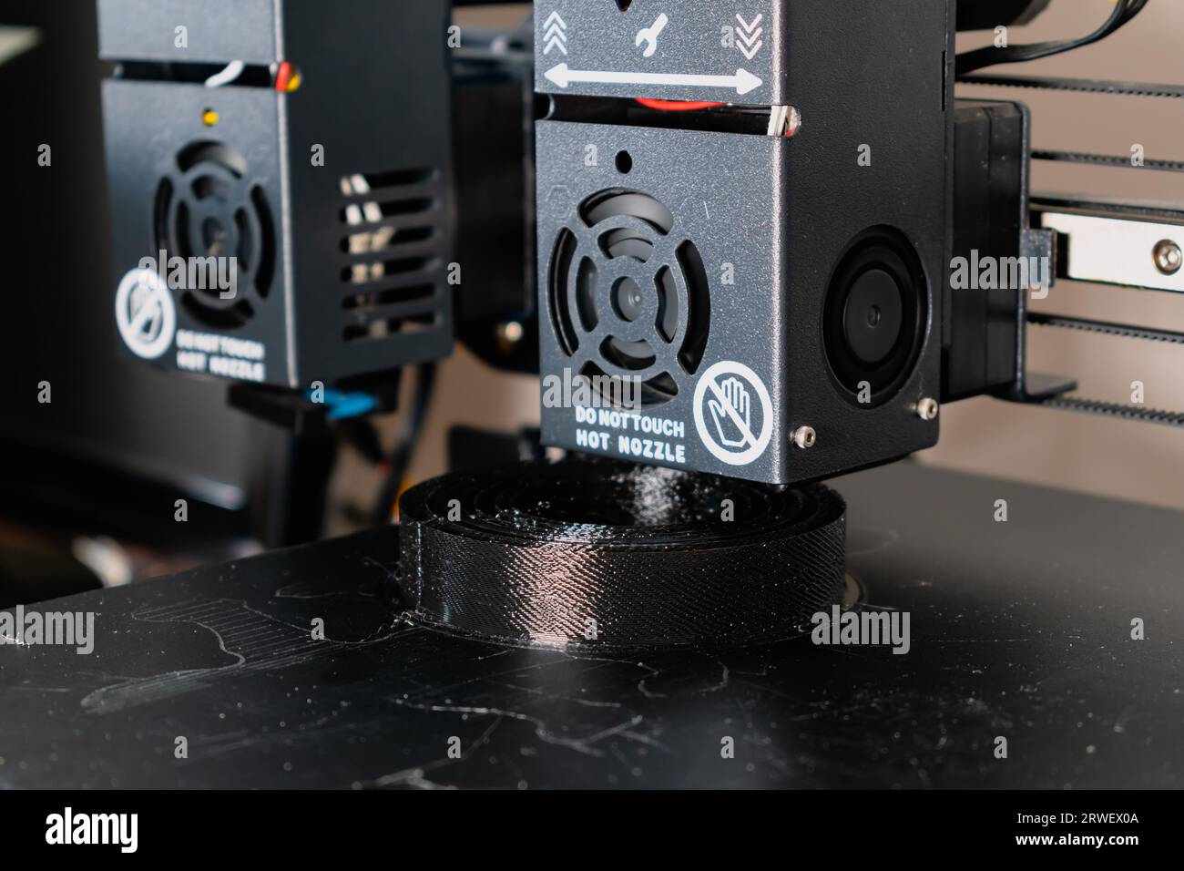Dual extruder 3d printer printing a black model, idex technology Stock