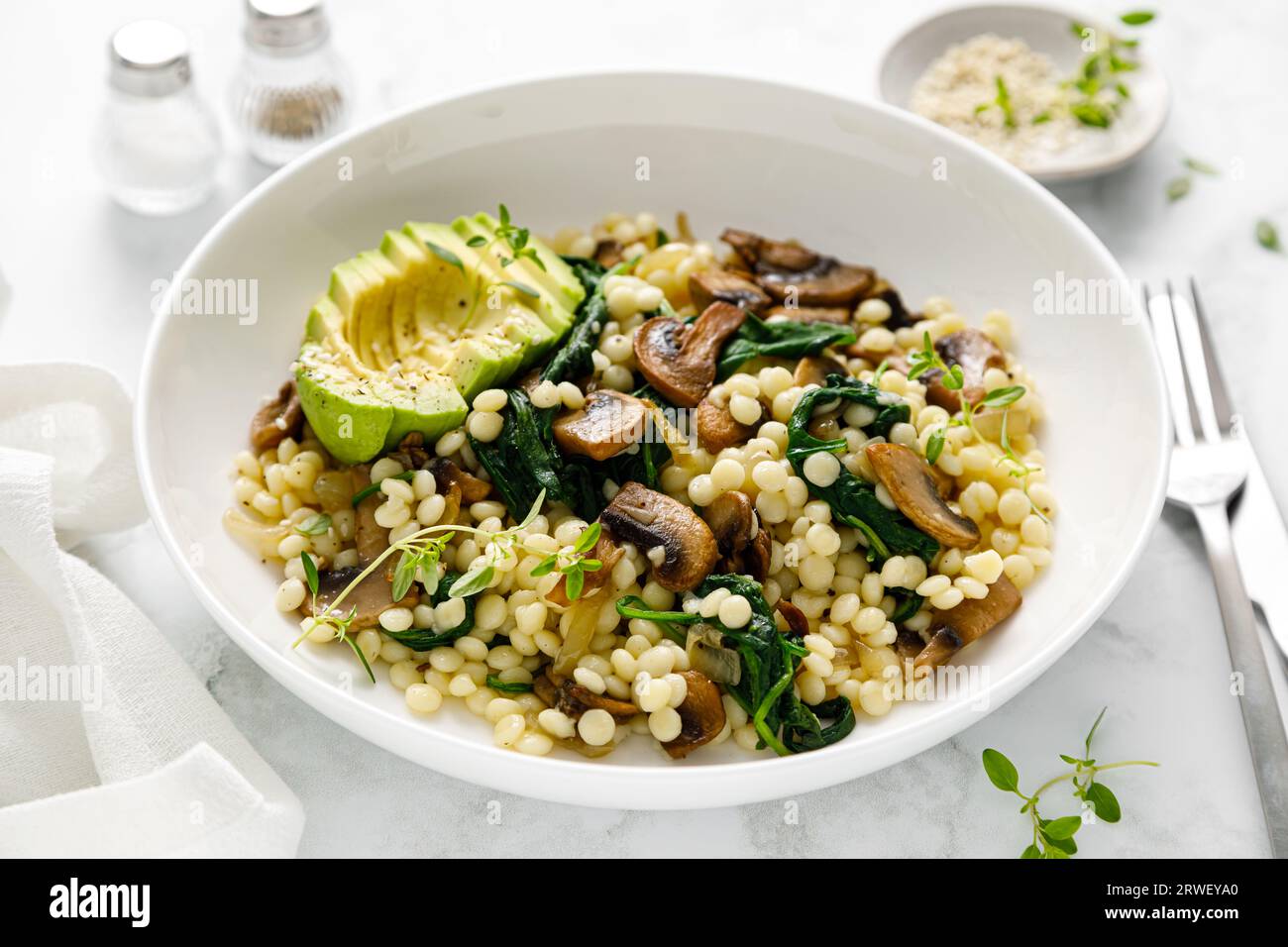 Couscous with avocado, spinach and sauteed champignon mushrooms with onion Stock Photo