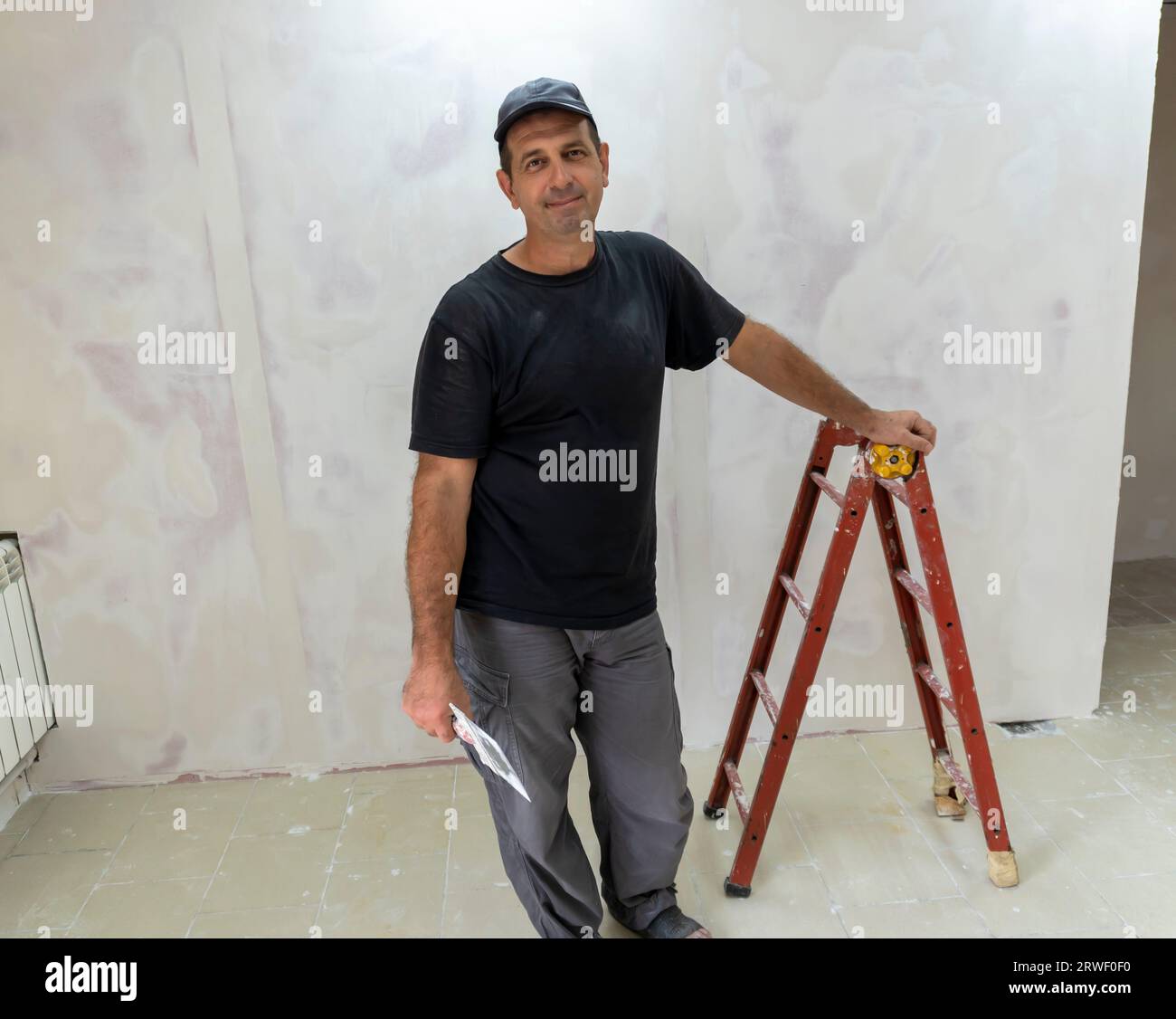 Male builder, master office, plasterer with a tool in working clothes Stock Photo