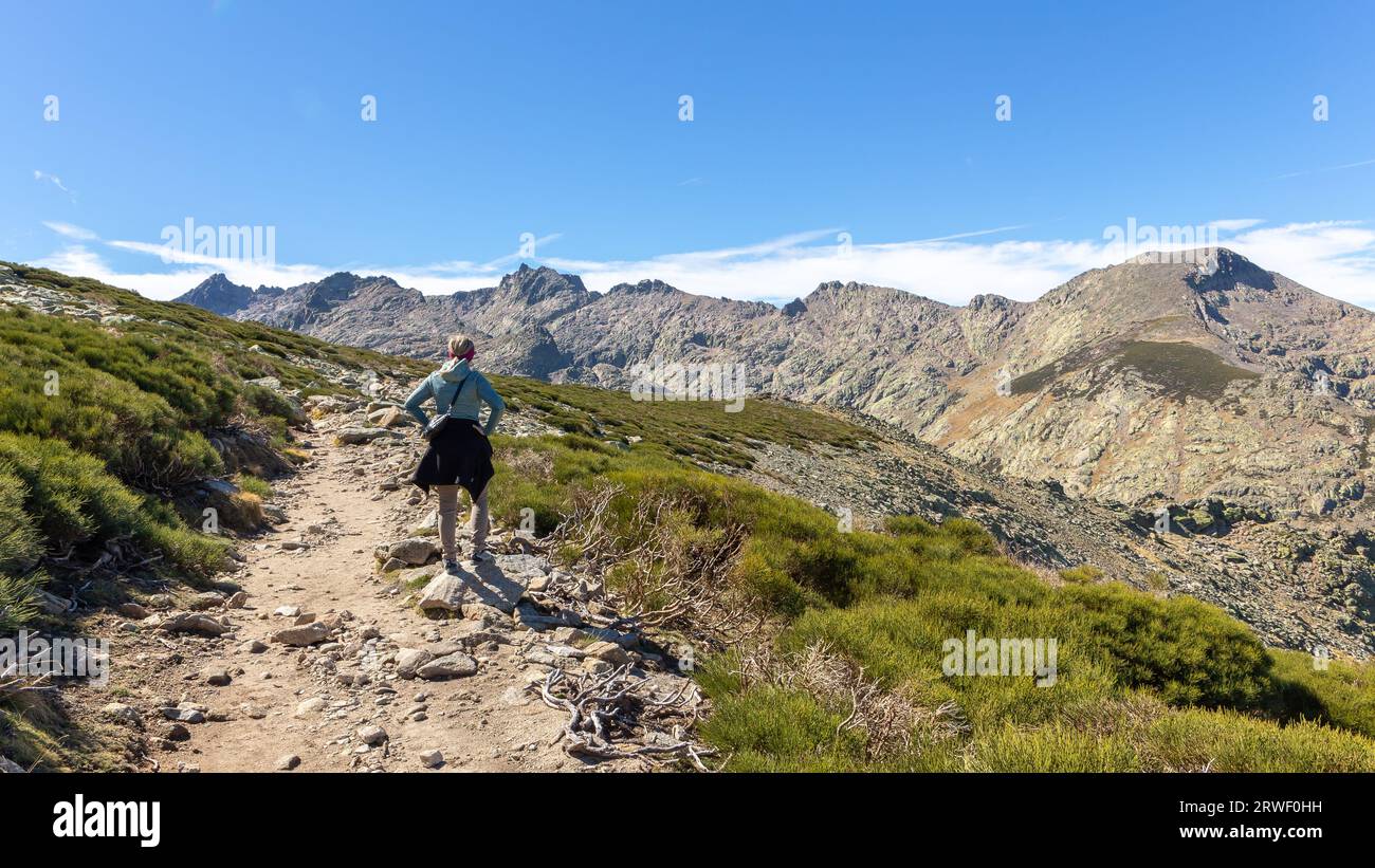 Female tourist on hiking trail to the Laguna Grande de Gredos lake from the Plataforma de Gredos in Sierra de Gredos mountains, Spain. Stock Photo