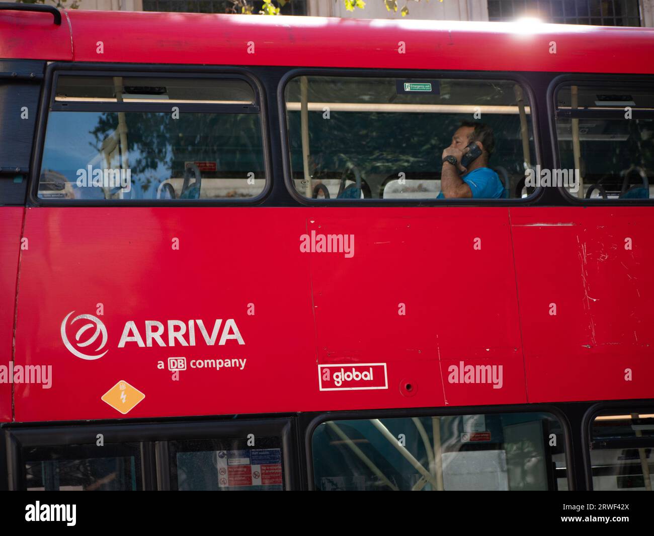 Man seated on Arriva red London bus using mobile phone in Central  London Stock Photo