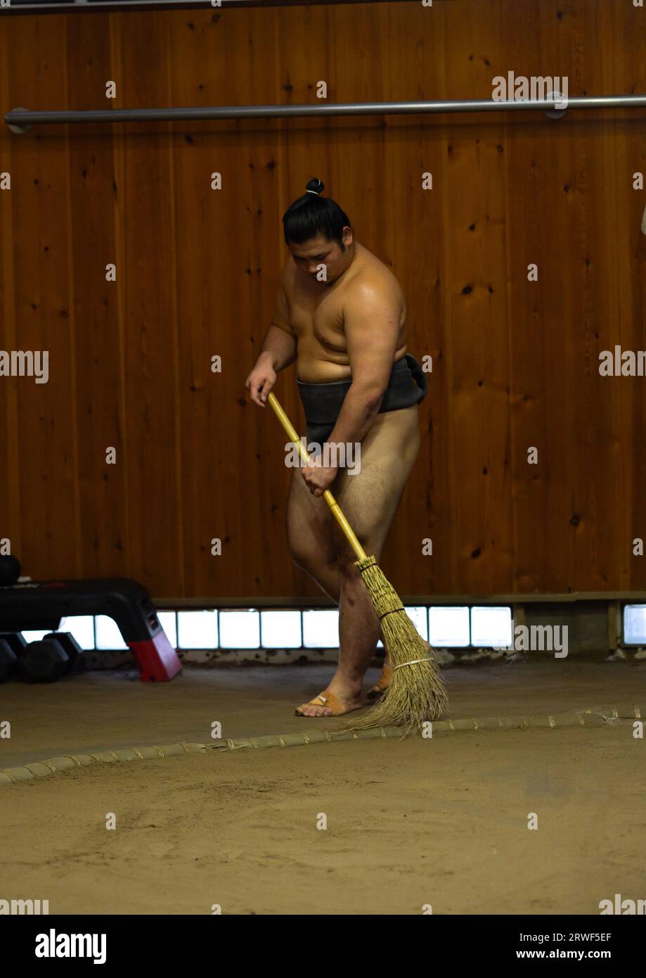 Sumo wrestler brooming the dohyo in Tatsunami Beya sumo stable, Kanto region, Tokyo, Japan Stock Photo