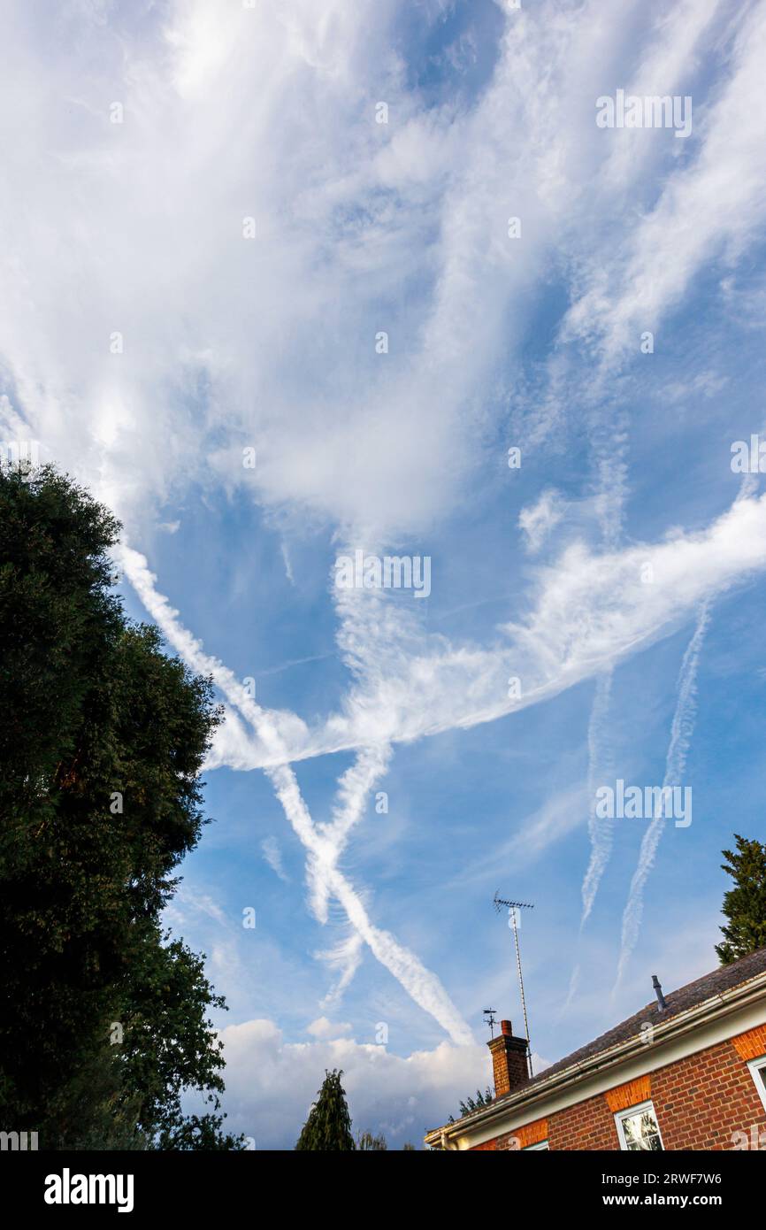 White criss-cross vapour trails from Heathrow bound aircraft forming triangular patterns against a blue sky in Surrey, south-east England Stock Photo