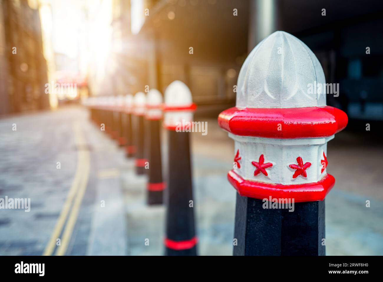 Traditional old-fashioned street bollards in London, UK. The cast iron Victorian style bollards are in the City streets, shown here with a sunshine ba Stock Photo